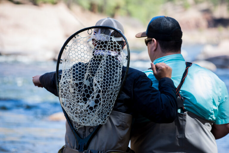 An Aspen Colorado fishing guide helping an amateur fisherman during a guided fly-fishing trip.