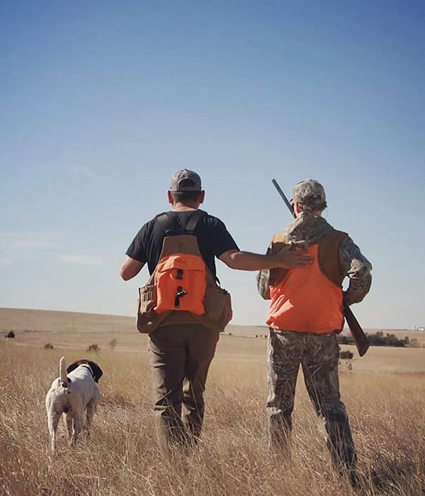 A hunting guide and his trained dog help a visitor while bird hunting in Western Colorado