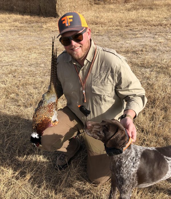 man holding a fowl and dog